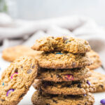 side view of colorful gluten-free monster cookies stacked on a marble slab