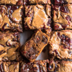 Top down image of raspberry almond flour blondies cut into squares on a piece of parchment