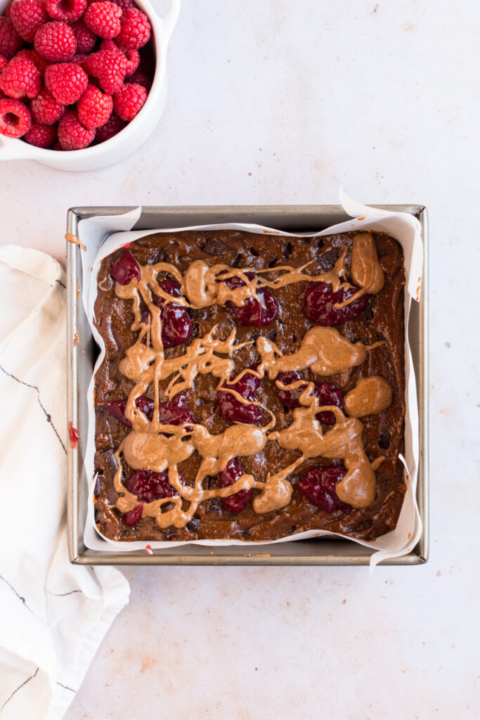 top down image of batch of raspberry almond flour blondies with almond butter and raspberry on top