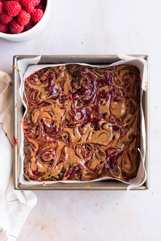 top down image of batch of raspberry almond flour blondies with almond butter and raspberry swirled on top