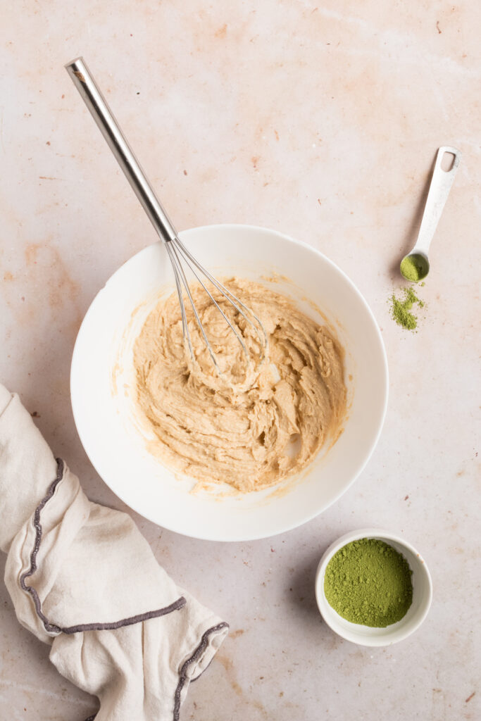 top down photo of butter and sugar being whipped together for matcha cookies in white bowl